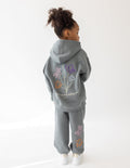 Kids wearing God's Still Working oversized hoodie in Sedona Sage with Psalm 138:8 embroidery