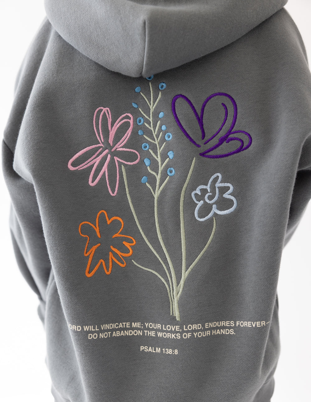 Kids wearing Sedona Sage God's Still Working hoodie with oversized fit and embroidered Psalm 138:8 design