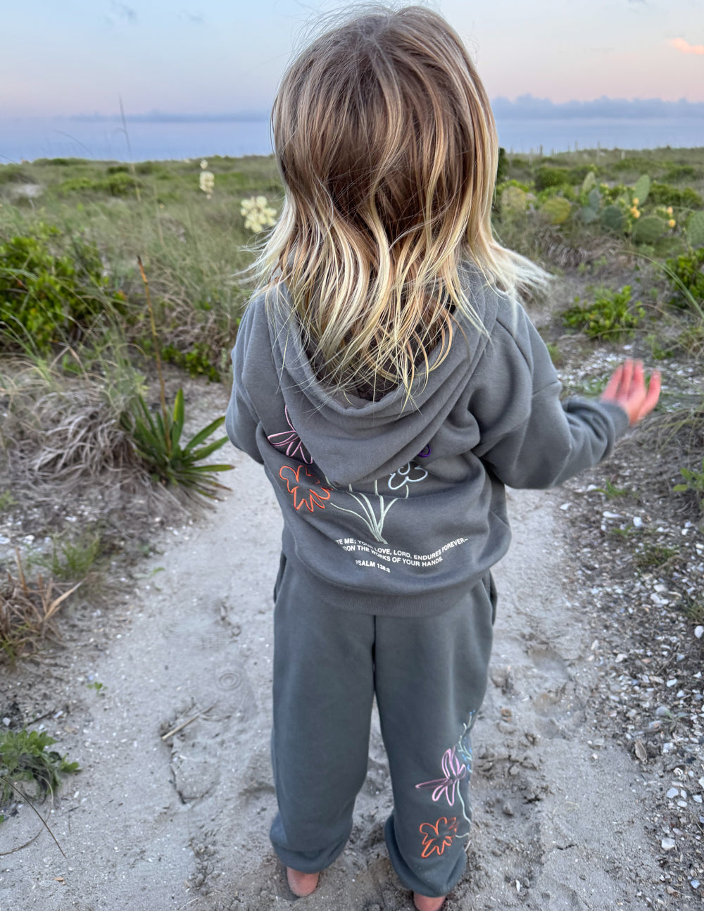 Kids wearing oversized God's Still Working hoodie in Sedona Sage with embroidered Psalm 138:8 design