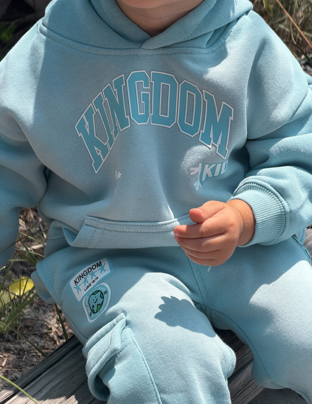 Child wearing oversized Kingdom Kids Hoodie in air blue with puff print design